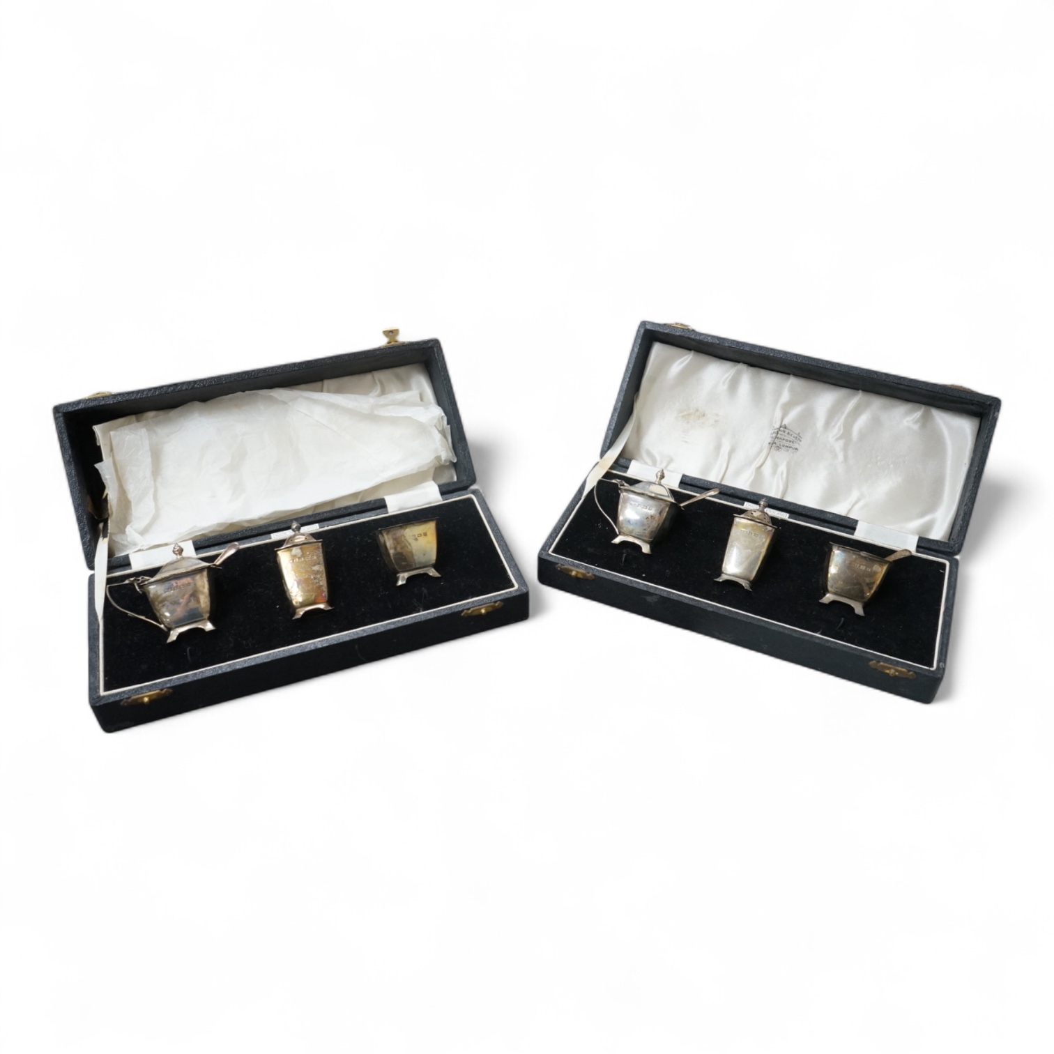 A pair of cased Elizabeth II silver three piece condiment sets, by William Adams Ltd, Birmingham, 1955, one spoon missing.